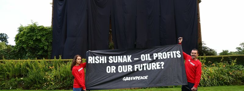 Greenpeace-Aktivisten mit einem Banner vor dem verhüllten Haus des britischen Premiers Rishi Sunak. - Foto: Luca Marino/Greenpeace/PA/dpa
