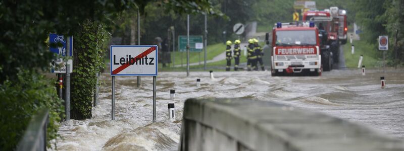Feuerwehrwagen stehen vor einer überfluteten Brücke über die Sulm am Ortsausgang von Leibnitz in der Steiermark. - Foto: Erwin Scheriau/APA/dpa