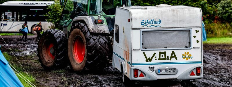 Ab durch den Schlamm: Ein Traktor zieht einen Wohnwagen vom Campinggelände des Wacken Open Air. - Foto: Axel Heimken/dpa