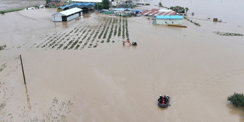 Rettungskräfte suchen auf einem Boot nach vermissten Personen im Hochwasser, nachdem der Tropensturm «Khanun» auf Land getroffen ist. - Foto: Yun Kwan-shick/Yonhap/AP/dpa