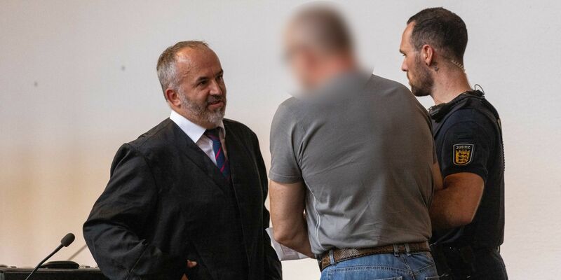 Der Angeklagte (M) spricht mit seinem Verteidiger (l) im Gericht. - Foto: Philipp von Ditfurth/dpa