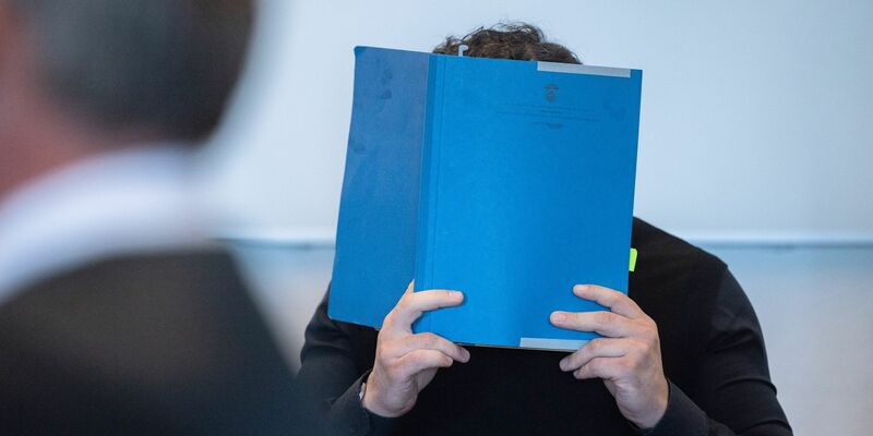 Einer der Hauptangeklagten versteckt zu Beginn des Prozess wegen Betrugs mit Corona-Tests sein Gesicht. - Foto: Rolf Vennenbernd/dpa