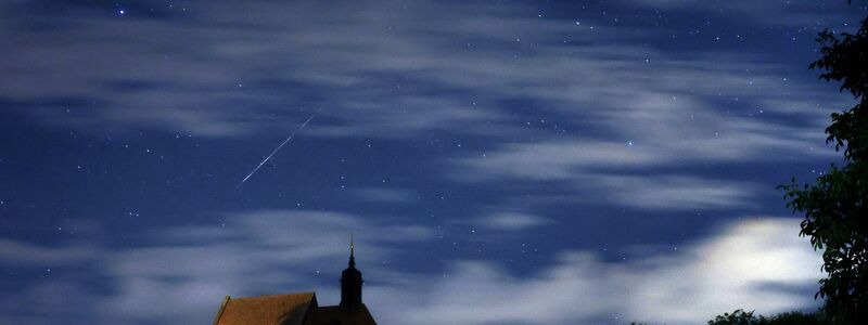 Eine Sternschnuppe verglüht am Himmel über der Wallfahrtskirche Maria im Weingarten. - Foto: Karl-Josef Hildenbrand/dpa