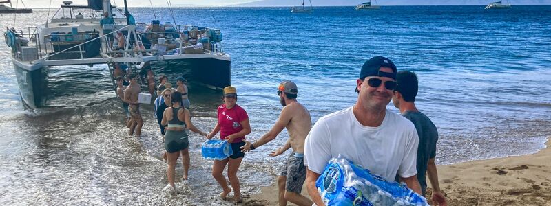 Freiwillige aus Maalaea Bay auf Maui entladen Spenden von einem Boot. - Foto: Rick Bowmer/AP/dpa