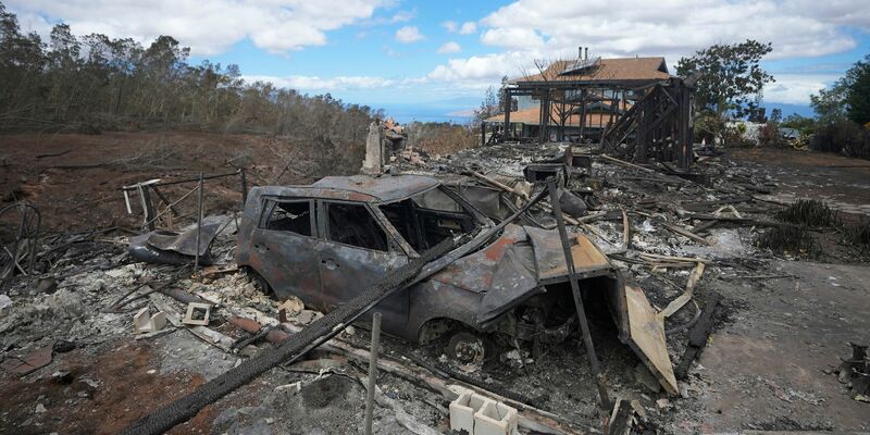 Die verkohlten Überreste eines Fahrzeugs stehen in Kula neben einem von einem Waldbrand zerstörten Haus. - Foto: Rick Bowmer/AP