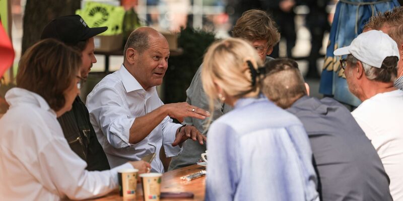 Bundeskanzler Olaf Scholz (M, SPD) spricht vor einem Büdchen mit Düsseldorfer Bürgern. - Foto: Oliver Berg/dpa