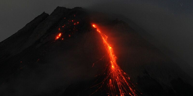 Der orange-rote Lavastrom leuchtet in der Dunkelheit. - Foto: Angga Budhiyanto/ZUMA Press Wire/dpa