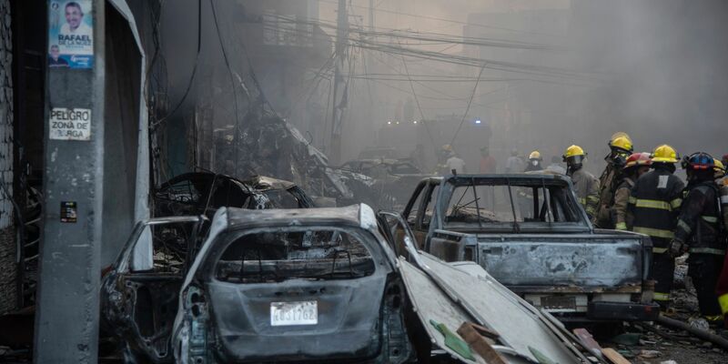 Feuerwehrleute arbeiten neben zerstörten Fahrzeugen nach einer starken Explosion, die ein Marktviertel mit vielen Geschäften erschüttert hat. - Foto: Jolivel Brito/AP/dpa