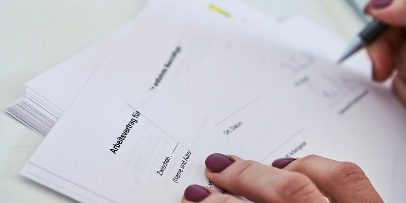 Eine Frau unterschreibt einen Arbeitsvertrag. - Foto: Annette Riedl/dpa