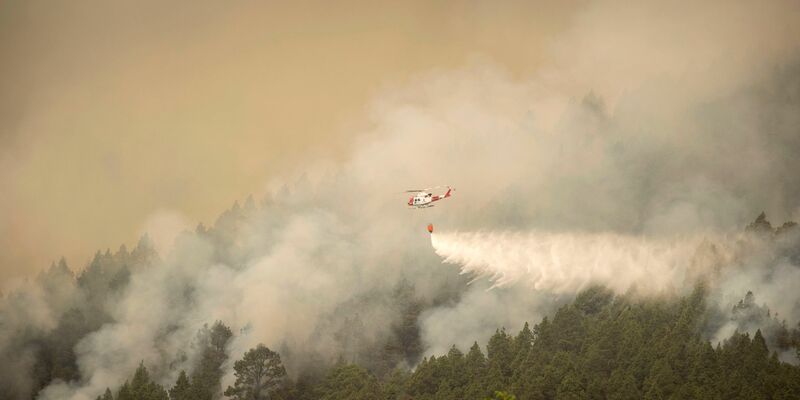 Ein Hubschrauber überfliegt einen Brand am Stadtrand von El Rosario während eines Löscheinsatzes. - Foto: Arturo Rodriguez/AP