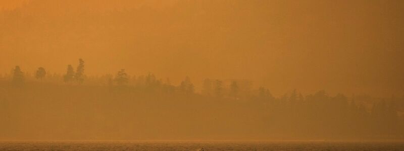 Ein Boot fährt auf dem Okanagan-See, während der Rauch des McDougall-Creek-Wildfeuers über dem Gebiet liegt. - Foto: Darryl Dyck/The Canadian Press via AP/dpa