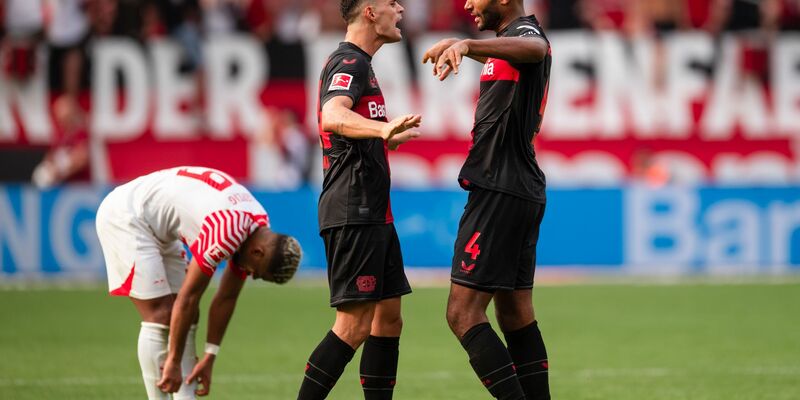 Leverkusens Granit Xhaka (M) und Jonathan Tah klatschen sich nach der Partie ab. Links Leipzigs Benjamin Henrichs. - Foto: Marius Becker/dpa