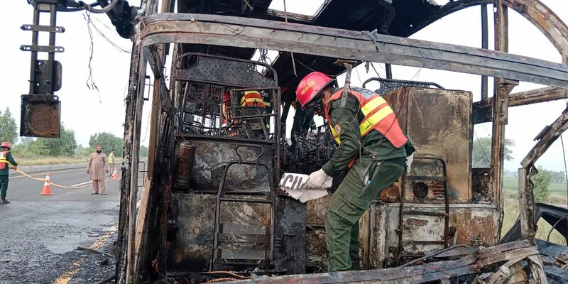 Rettungskräfte untersuchen den verbrannten Bus an der Unfallstelle auf einer Autobahn. - Foto: Uncredited/Rescue 1122 Emergency Department/AP/dpa