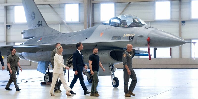 Wolodymyr Selenskyj (2.v.r) und Mark Rutte (M) laufen an einem F-16 Kampfjet vorbei. - Foto: Peter Dejong/AP/dpa