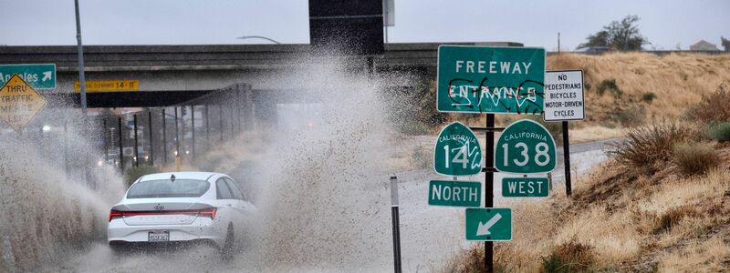Ein Fahrzeug fährt durch eine überflutete Autobahnauffahrt nahe der kalifornischen Stadt Palmdale. - Foto: Richard Vogel/AP