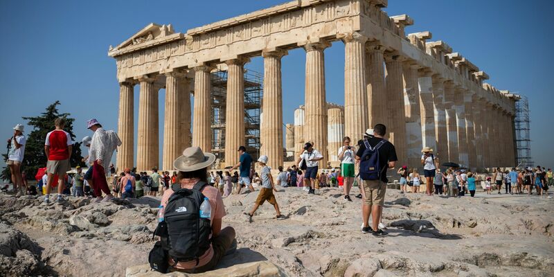 Touristen in Athen gehen an einem heißen Tag bei ihrem Besuch des Parthenon-Tempels auf dem Akropolis-Hügel. - Foto: Angelos Tzortzinis/dpa