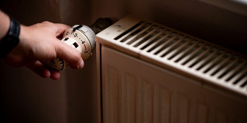 Eine Person benutzt einen alten Heizkörper in einer Berliner Altbauwohnung. - Foto: Fabian Sommer/dpa