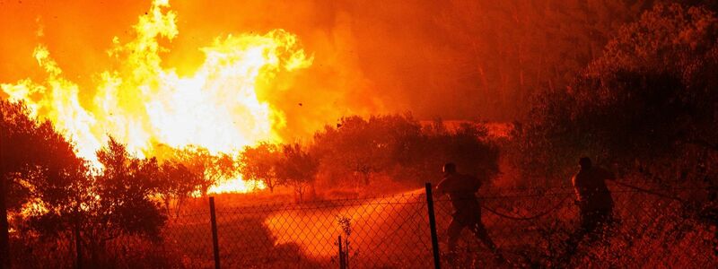 Ein Hubschrauber wirft Wasser über dem Dorf Avantas ab. Stürmische Winde fachen die Flammen der Waldbrände in ganz Griechenland an. - Foto: Achilleas Chiras/AP