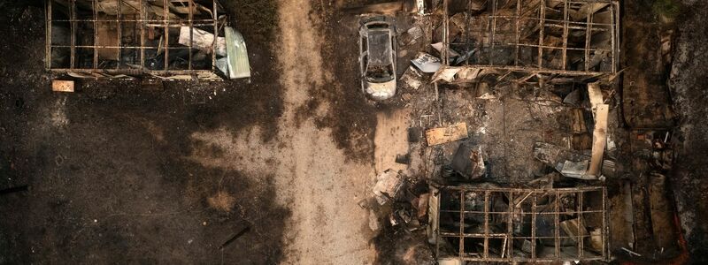 Ein verbranntes Auto und ausgebrannte Lagerhäuser in Palagia. - Foto: Achilleas Chiras/AP/dpa