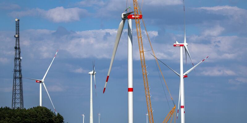 Ein Kran hebt auf der Baustelle eines neuen Windparks in Mecklenburg-Vorpommern ein Rotorblatt für die Montage an das Generatorhaus. - Foto: Jens Büttner/dpa