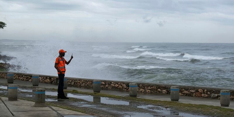 Menschen waten in Santo Domingo durch knietiefes Wasser auf einer Straße, die von den Regenfällen überflutet wurde. - Foto: Ricardo Hernandez/AP/dpa