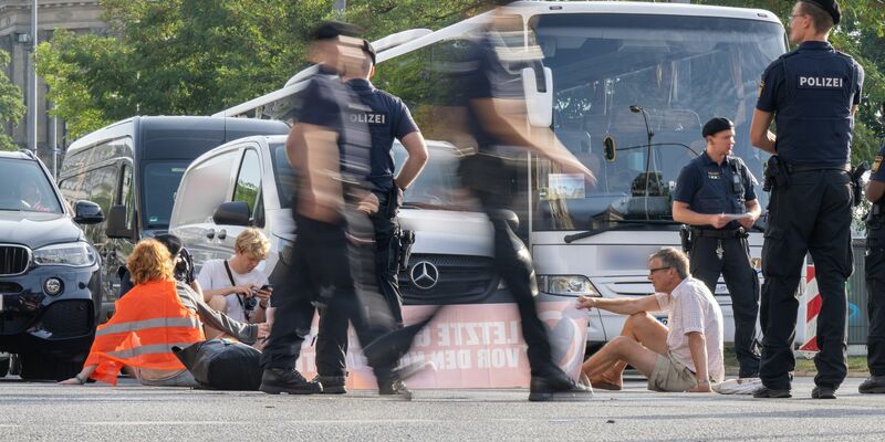 Polizisten halten an der Kreuzung am Stachus in der Münchner Innenstadt Klimaaktivisten der Letzten Generation fest. - Foto: Peter Kneffel/dpa
