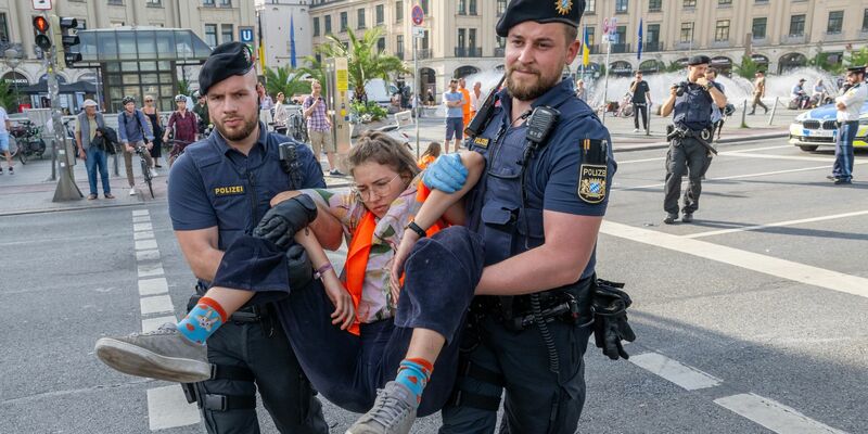 Polizisten tragen auf der Kreuzung am Stachus in der Münchener Innenstadt Aktivisten der Letzten Generation weg. Ihre Aktionen werden teilweise verboten. - Foto: Peter Kneffel/dpa