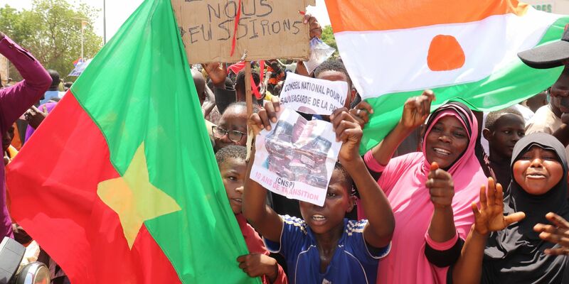 Befürworter des Putschs halten eine Flagge von Burkina Faso (l) und Niger hoch. Die beiden Länder haben einen Pakt geschlossen. - Foto: Djibo Issifou/dpa