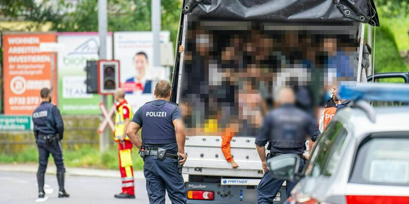 Polizisten stehen bei einer Kontrolle in Österreich an einem Kleintransporter. Die Beamten entdeckten dabei 53 Personen auf der Ladefläche. - Foto: Werner Kerschbaummayr/Fotokersch/APA/dpa
