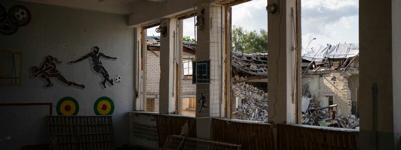 In Kupjansk ist durch die zerbrochenen Fenster einer Turnhalle die zerstörte Bibliothek einer Schule zu sehen. - Foto: Bram Janssen/AP