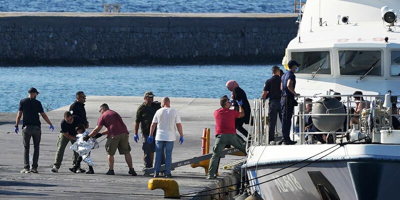 Menschen werden nach der Rettungsaktion im Hafen von Mytilini auf Lesbos von Beamten der Küstenwache eskortiert. - Foto: Panagiotis Balaskas/AP/dpa