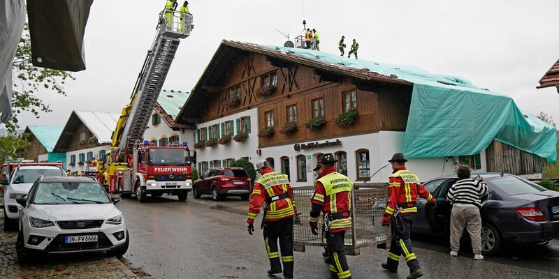 Arbeiter und Feuerwehrleute beseitigen die Unwetter-Schäden im oberbayerischen Bad Bayersoien. Bei dem Unwetter wurden viele Dächer beschädigt. - Foto: Uwe Lein/dpa