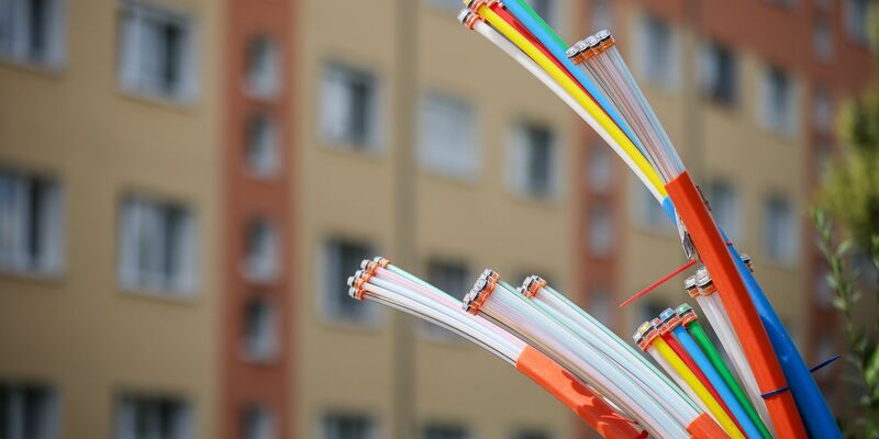 Aus dem Sockel eines Schaltschranks ragen Glasfaserkabel heraus. Beim Breitbandausbau sieht die Lage inzwischen deutlich besser aus als noch vor zwei Jahren. - Foto: Jan Woitas/dpa