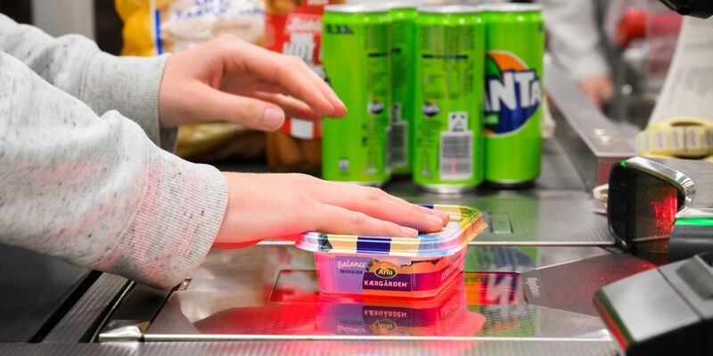 Eine Kassiererin scannt Lebensmittel an der Kasse eines Supermarktes. - Foto: Julian Stratenschulte/dpa