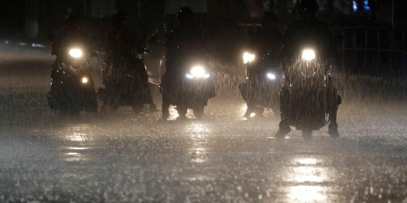 Rollerfahrer stehen bei heftigem Regen an einer Kreuzung in Taipeh. - Foto: Chiang Ying-ying/AP