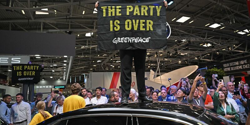 Eine Greenpeace-Aktivistin bei der Eröffnung der IAA auf dem Dach eines ausgestellten Autos. - Foto: Sven Hoppe/dpa