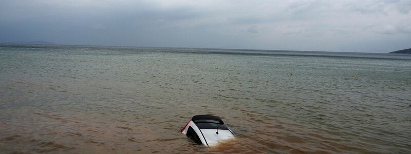 Ein Auto ist nach einem Rekordregen in Milina fast ganz im Meer versunken. - Foto: Thodoris Nikolaou/AP/dpa