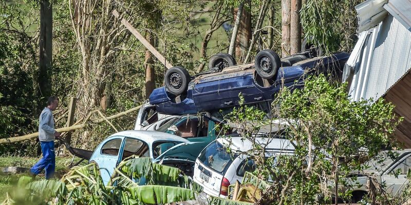 Ein Mann schiebt nach Überschwemmungen eine Schubkarre an zerstörten Autos vorbei. - Foto: Wesley Santos/AP/dpa