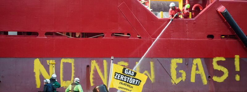 Greenpeace-Aktivisten mit einem Schlauchboot vor einem Schiff im Hafen von Mukran. - Foto: Gregor Fischer/Greenpeace Germany/dpa
