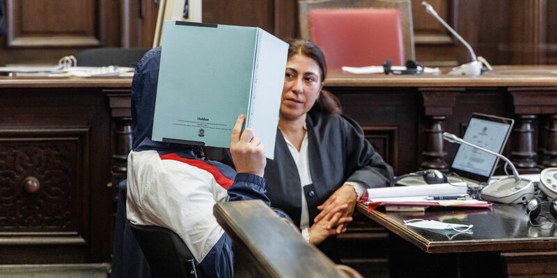 Der Angeklagte verbirgt zu Prozessbeginn sein Gesicht hinter einem Aktenordner. Er soll seine im Rollstuhl sitzende Großmutter getötet haben. - Foto: Markus Scholz/dpa