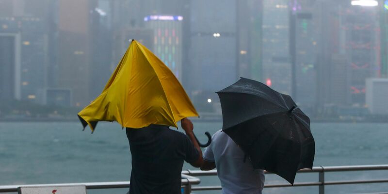Menschen mit Regenschirmen kämpfen in Hongkong mit starkem Wind und Regen des Taifuns «Saola». - Foto: Daniel Ceng/AP/dpa