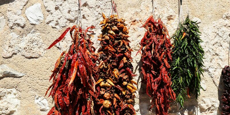 Getrocknete Paprikas und Chillis hängen auf einem Markt zum Verkauf. - Foto: Jens Kalaene/dpa-Zentralbild/dpa