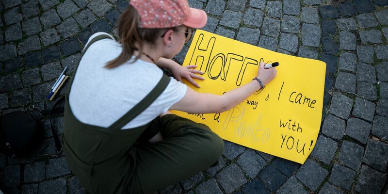 Eine junge Frau schreibt auf ein Schild: «Harry, I came all the way to take a photo with you!» - Foto: Fabian Strauch/dpa