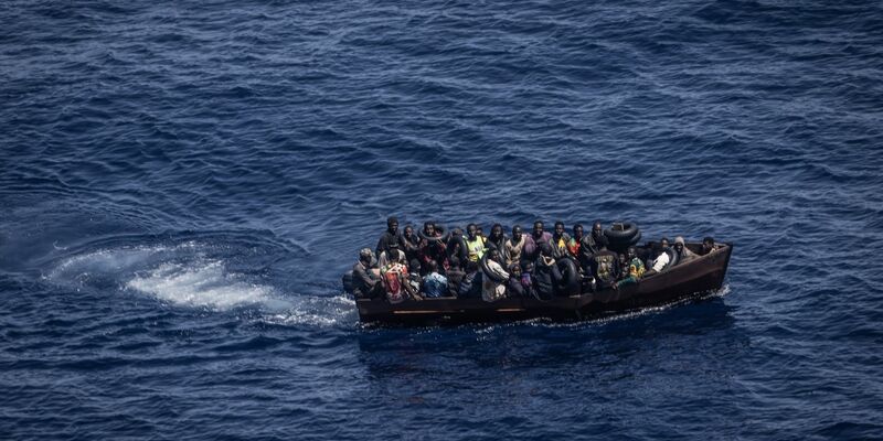 Migranten steuern ein Boot in Richtung der Insel Lampedusa. - Foto: Oliver Weiken/dpa