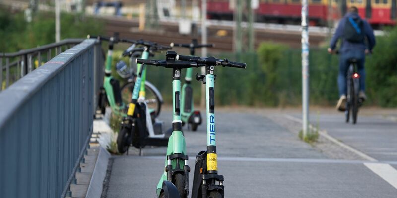 Elektroroller verschiedener Anbieter stehen nahe dem Berliner Bahnhof Ostkreuz auf einem Gehweg. - Foto: Soeren Stache/dpa