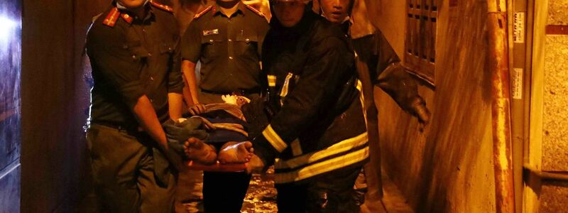 Rettungskräfte tragen eine Person aus dem brennenden Gebäude in Hanoi. - Foto: Pham Trung Kien/VNA/AP/dpa