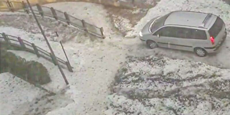 Ein Van fährt nach einem heftigen Hagelschauer über einen winterlich anmutenden Parkplatz in Worms. - Foto: Einsatz-Report24/dpa