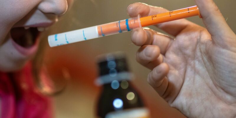 Eine Mutter verabreicht ihrer Tochter eine Dosis Fiebersaft. (Symbolbild) - Foto: Hendrik Schmidt/dpa