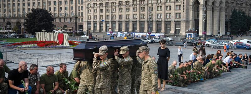 Menschen in Kiew knien nieder, während Soldaten den Sarg eines Kameraden tragen, der in einem Gefecht getötet wurde. - Foto: Efrem Lukatsky/AP/dpa