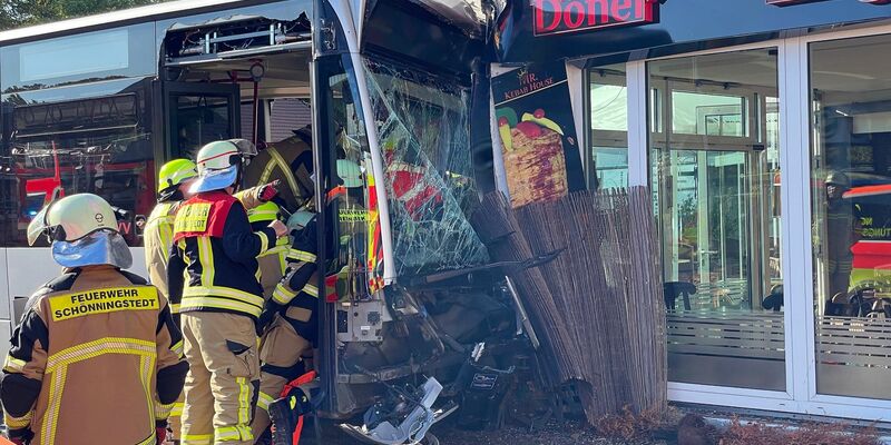Einsatzkräfte der Feuerwehr untersuchen den  Linienbus, der zuvor in einen Dönerladen gekracht war. - Foto: Schröder/NEWS5/dpa